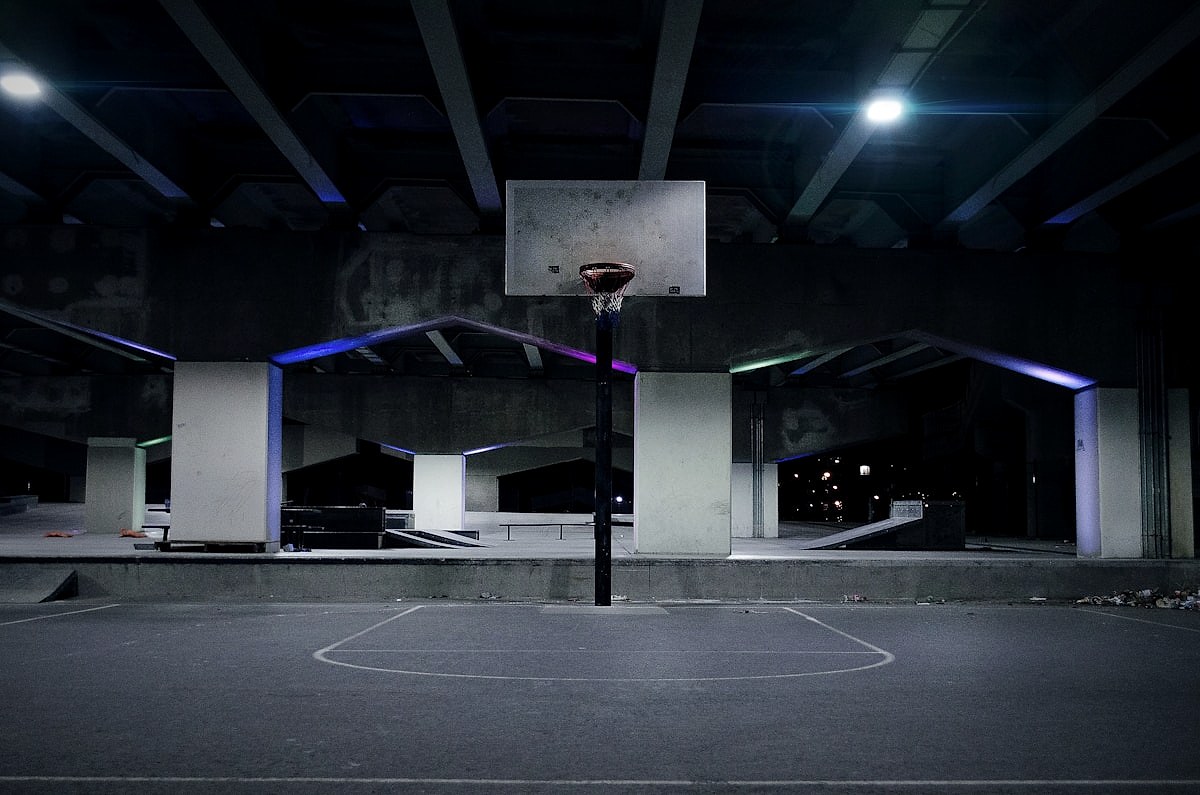 An empty basketball court under arena lights