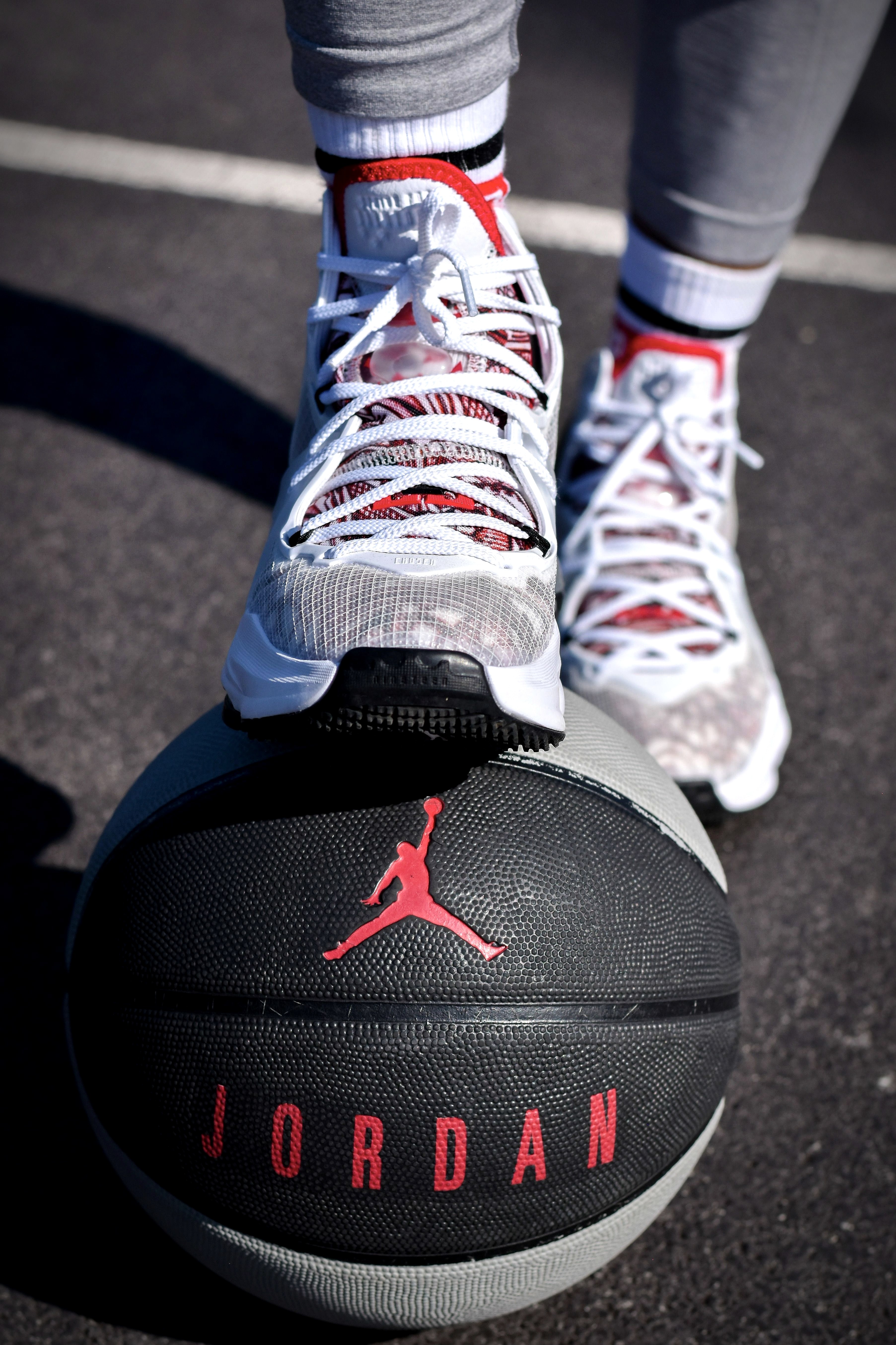 White Air Jordan sneakers resting on a basketball on an outdoor court